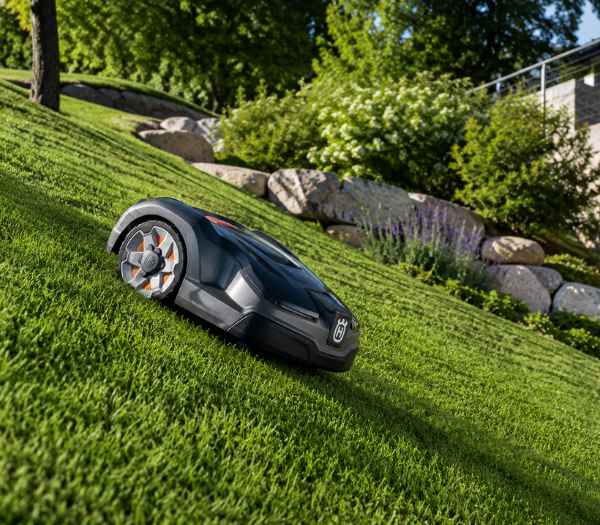 Robot cortacésped trabajando en un jardín con pendiente